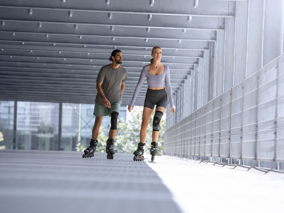 Orthopaedics A man and a woman wearing knee braces are rollerblading in a garage.