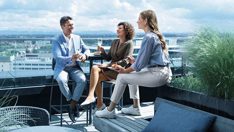 A man and two women wearing compression stockings are on a roof terrace