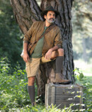 Lifestyle image Juzo Adventure Man wears Juzo Adventure in poppy and stands in the meadow by a tree