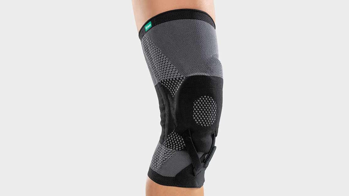 A woman is sitting on the floor in the gym. She is wearing a knee brace A woman is sitting on the floor in the gym. She is wearing a knee brace