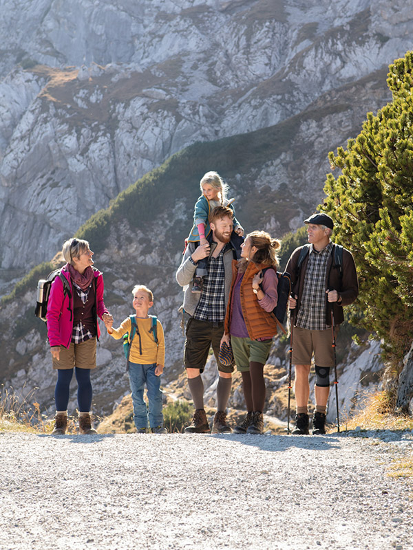 A group of hikers with children on a sunny mountain path; some are wearing compression stockings and bandages A group of hikers with children on a sunny mountain path; some are wearing compression stockings and bandages