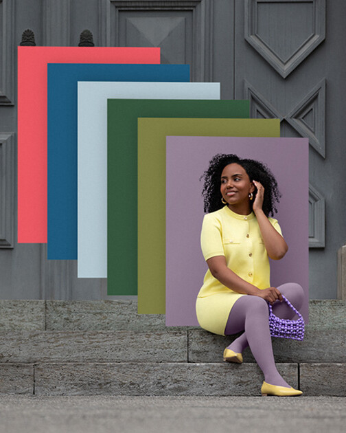 A woman wearing compression stockings in the colour Cozy Violet is sitting on a flight of stairs. In the background are the colour swatches of the current Juzo Trend Colours.