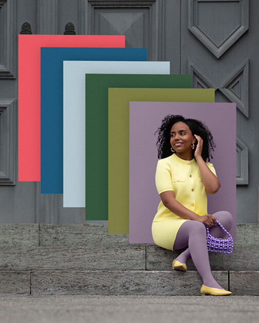 A woman wearing compression stockings in the colour Cozy Violet is sitting on a flight of stairs. In the background are the colour swatches of the current Juzo Trend Colours.
