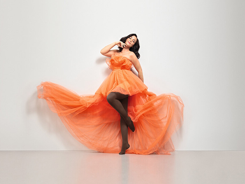 A woman in an orange dress. She is wearing Juzo Inspiration brown tights.