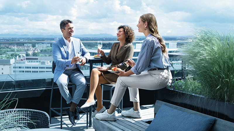 Un uomo e due donne con calze a compressione si trovano su una terrazza sul tetto